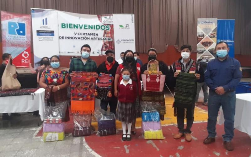 Personas de pie posan para foto donde muestran sus trabajos elaborados.