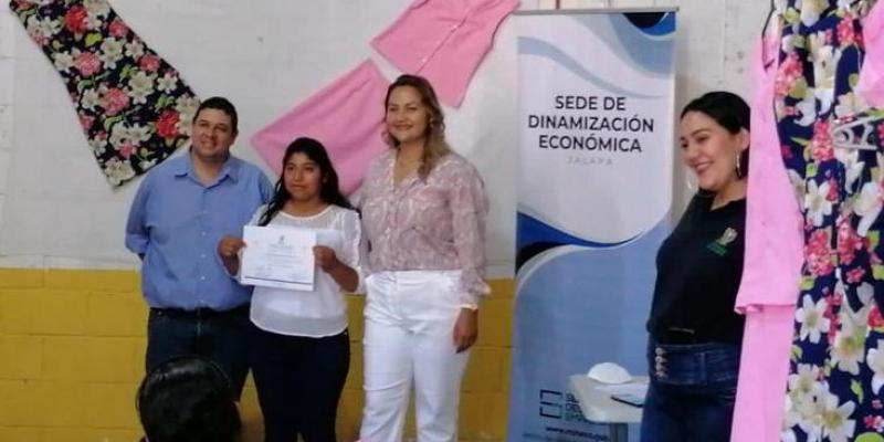 4 personas posan sobre fondo con imagen del Ministerio de Economía recibiendo diplomas 
