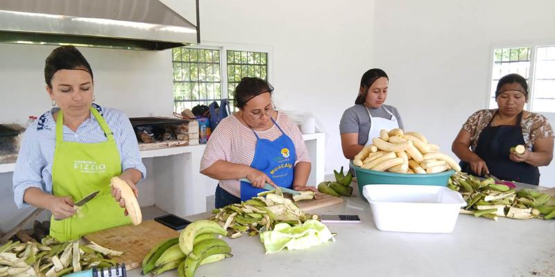 Mujeres de Colpetén preparan harina de plátano para evento de intercambio 